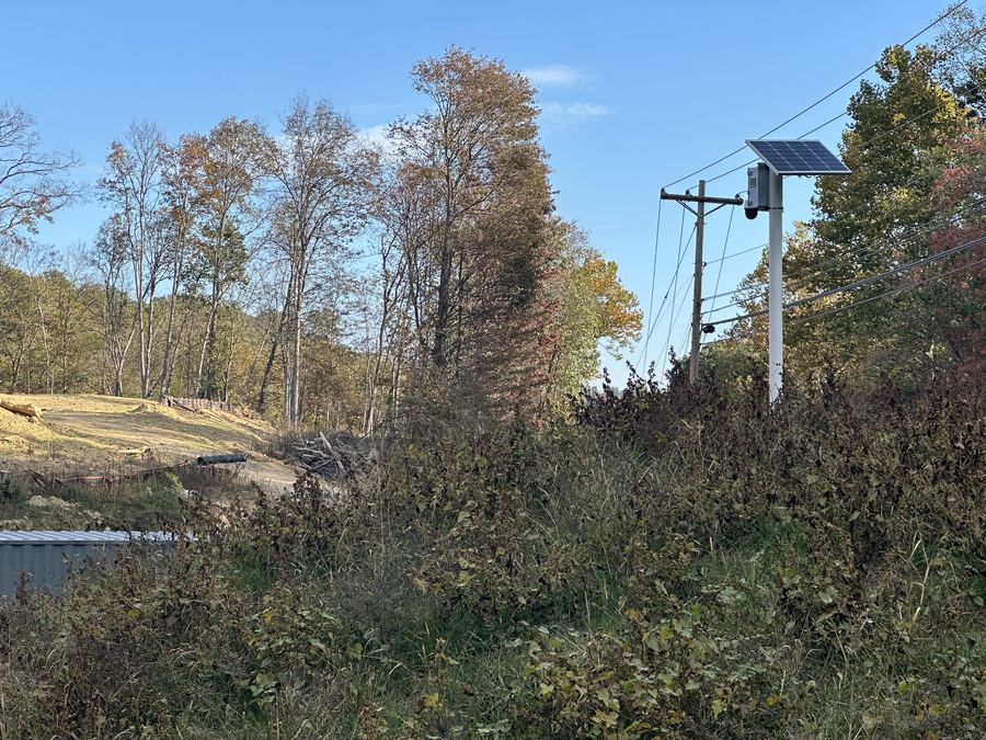 Pole-mounted solar camera overlooking a cleared rural site