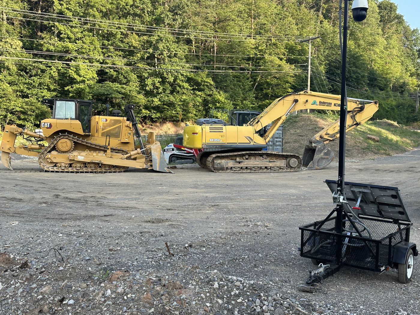 Mobile surveillance trailer with mast camera guarding heavy equipment on an active job site